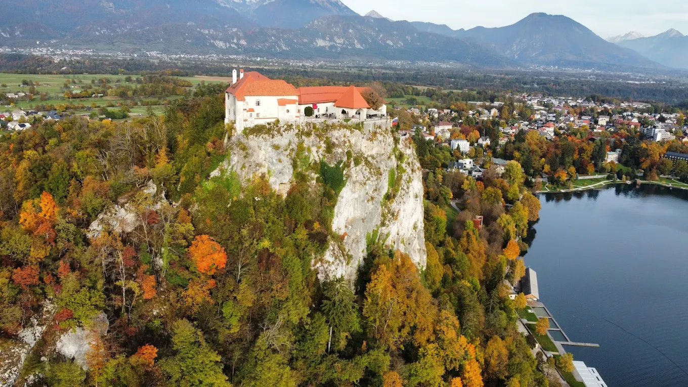 Bled Castle on its cliff in autumn with fall colors and the town below